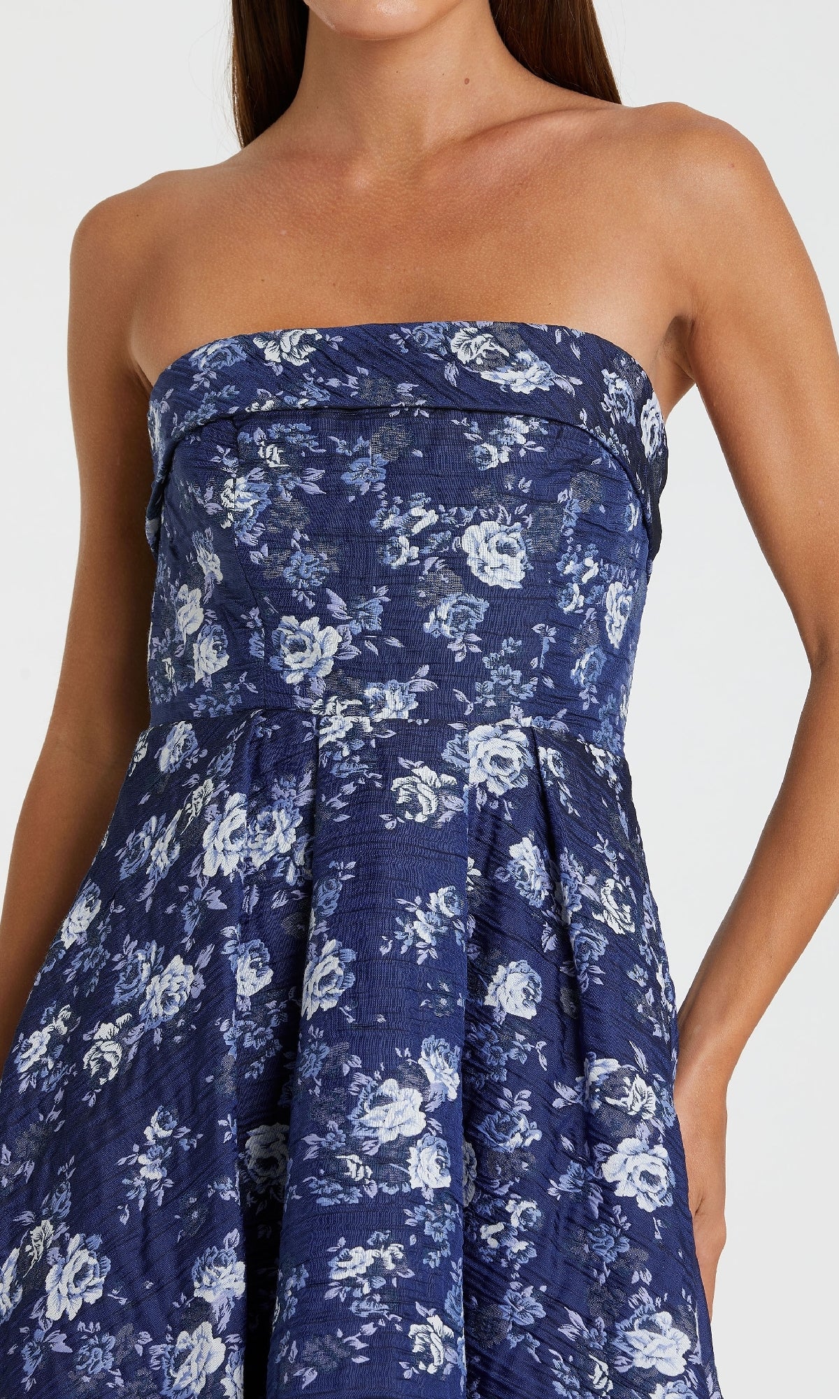 A woman wears the Mac Duggal 68617 Strapless Wedding Guest Dress—a chic tea-length party dress with a dark blue base and light blue floral print.